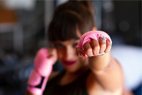 photo of smiling woman in boxing gloves, symbolic of beating cancer by Sarah Cervantes on Unsplash